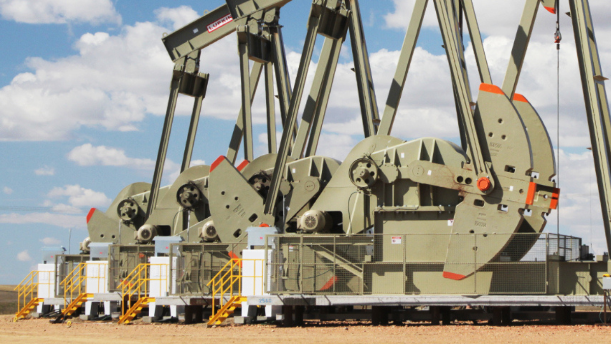 Row of Lufkin pumpjacks operating in an oilfield under blue sky